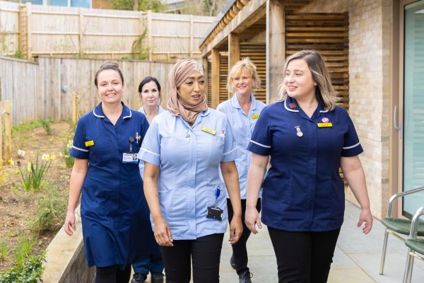 Team of professional nurses from Martlets walking together outdoors.