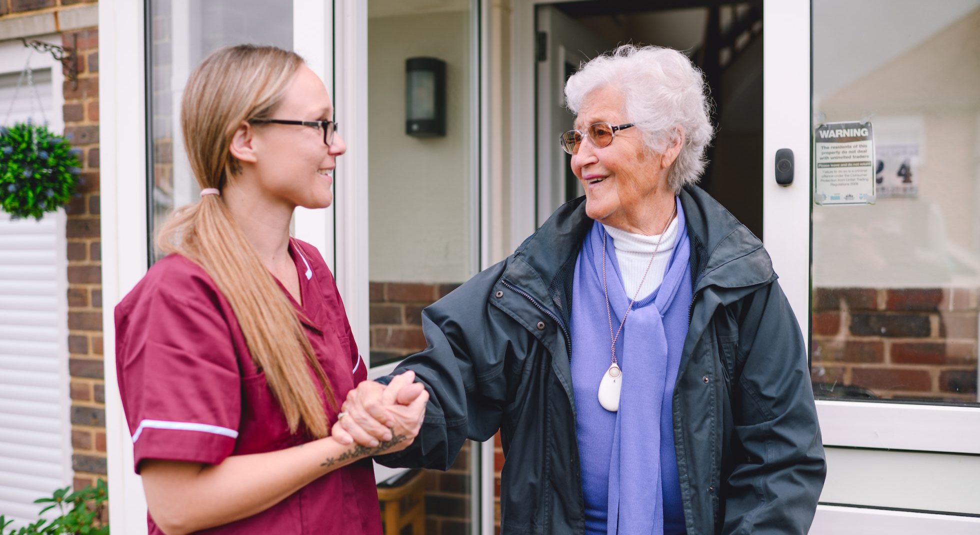 Home care assistant helping an elderly woman outside her home in Brighton and Hove.