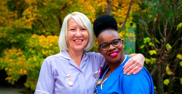 Two smiling St Barnabas House nurses standing together outdoors.